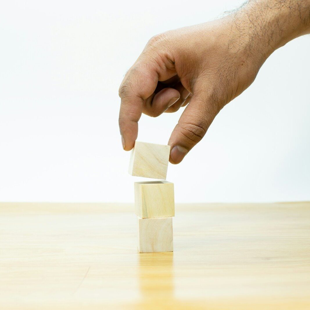 A hand is placing a block of wood on a table