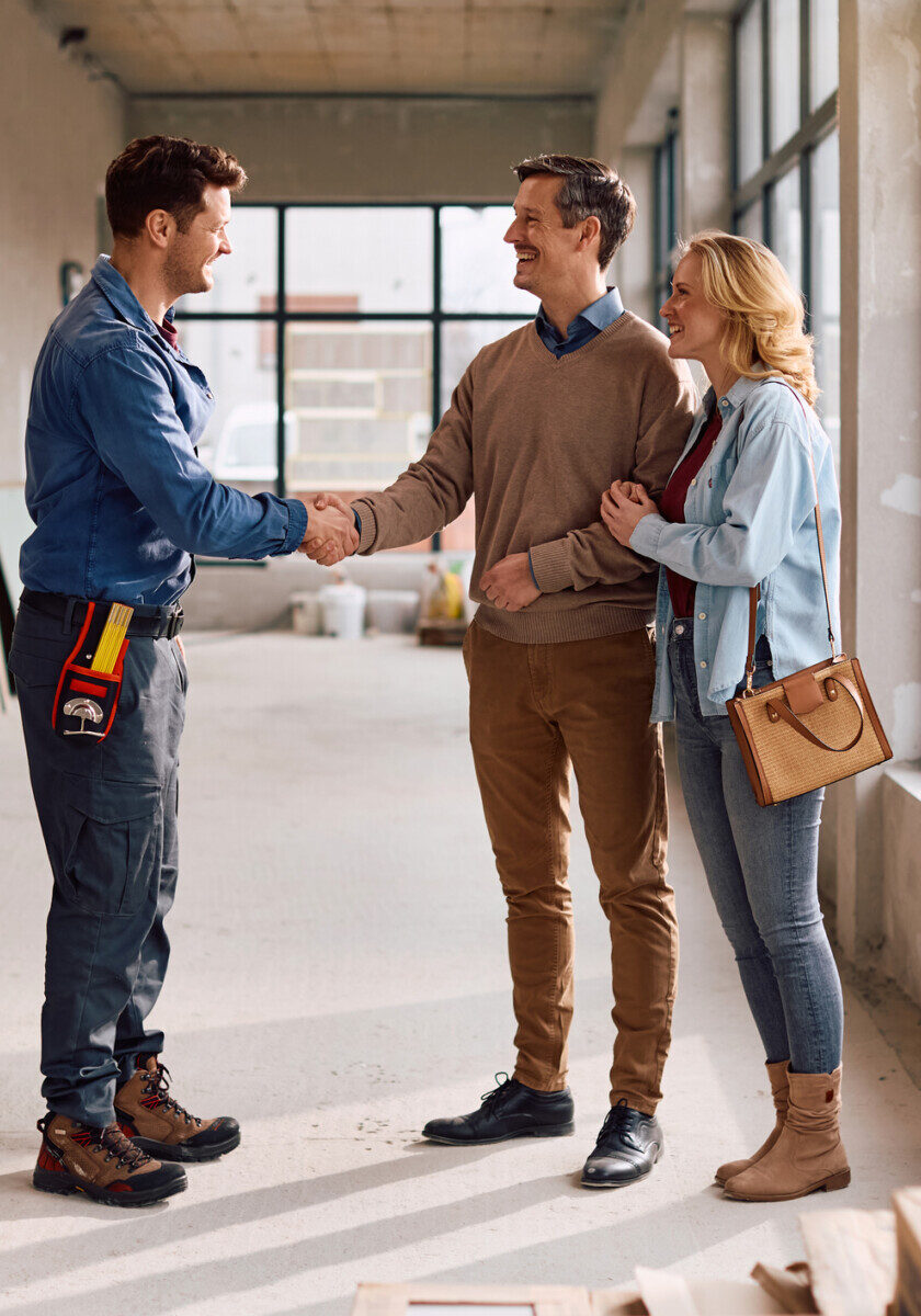 Happy construction worker greeting his clients during home improvement project.